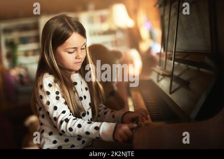 Learning the notes to all the keys. Cropped shot of a little girl playing the piano at home. Stock Photo