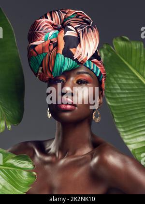 More than just cloth, its my crown. Studio shot of a beautiful young woman wearing a traditional African head wrap against a leafy background. Stock Photo