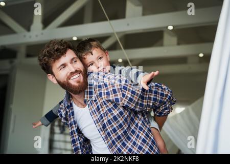 Where to, Mr Pilot. Cropped shot of an adorable little boy on his dads back with his arms stretched out. Stock Photo