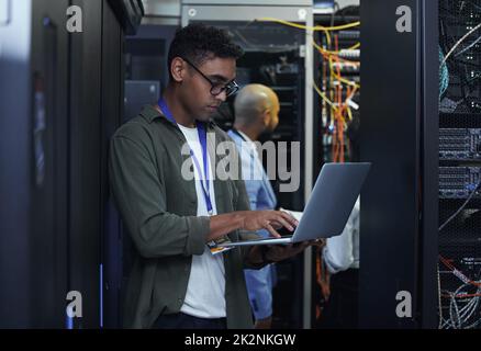 IT work in progress. Cropped shot of two male IT support agents working together in a dark network server room. Stock Photo