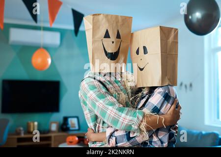 We love being silly together. Shot of a young couple with paper bags over their heads at home. Stock Photo