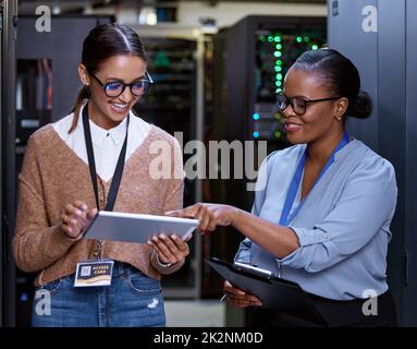 Those speeds are amazing. Cropped shot of two attractive young female computer programmers working together in a server room. Stock Photo