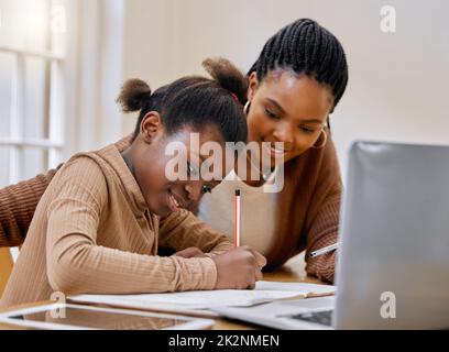 Mom always knows the best methods. Shot of a young mother helping her daughter with homework at home. Stock Photo