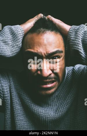 My mind is making a monster out of me. Studio shot of a young man experiencing mental anguish and screaming against a black background. Stock Photo