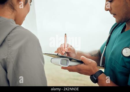 Getting the formalities out of the way. Cropped shot of a handsome young male physiotherapist filling out paperwork during a session with a female patient outside. Stock Photo