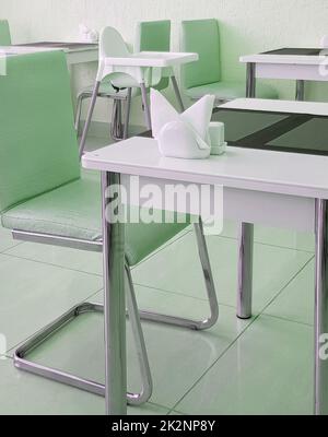 Stylish modern interior of the dining room with designer tables and chairs, green tinting Stock Photo