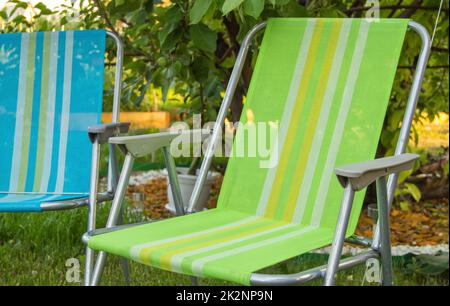 Two garden folding chairs stand in the shade under a tree on a hot summer day in the garden, close-up Stock Photo