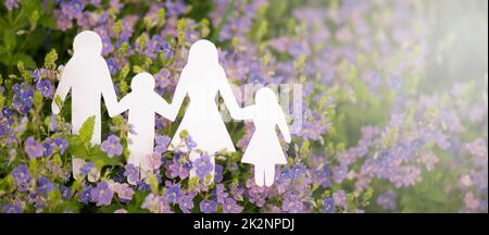 Family paper cut out is standing in a meadow, parents with daughter and son, environment concept, spring and summer season Stock Photo