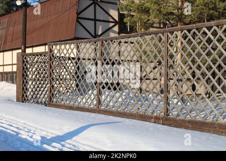 Beautiful bright house with a reddish-brown roof and a patterned carved fence. Winter. Stock Photo