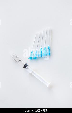 There is a syringe and injection needles on a white table. The concept of vaccination and health. View from above. Stock Photo