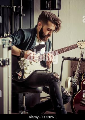 Playing his electric guitar in the recording studio Stock Photo