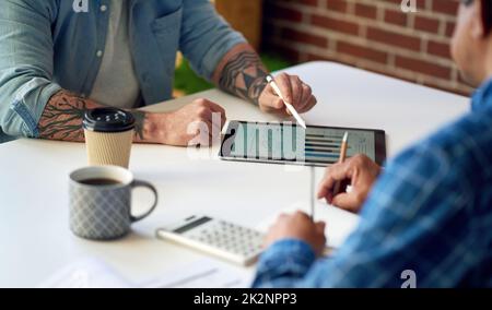 two businessmen using tablet computer discussing financial graph data on mobile touchscreen device in meeting Stock Photo