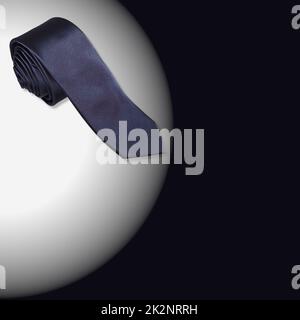 A navy blue rolled male necktie isolated on white and black background with copyspace Stock Photo