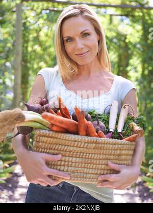 Celebrating a bountiful harvest. A woman holding a basket of fresh vegetables. Stock Photo