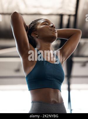 Now THAT, was a workout. Low angle shot of an attractive and athletic young woman looking exhausted while standing with her hands behind her head in the gym. Stock Photo