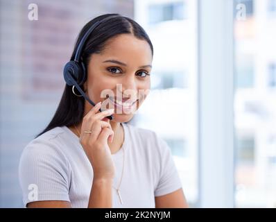 Im here to solve your problems. Cropped portrait of an attractive young female call center agent working at her desk in the office. Stock Photo