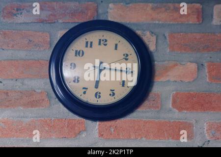 The black clock is on the old brick wall. Stock Photo