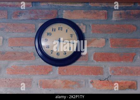 The black clock is on the old brick wall. Stock Photo