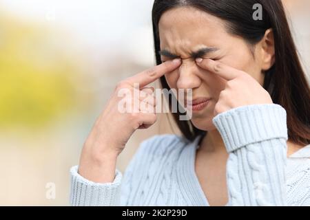Woman scratching itchy eyes with her hands in a park Stock Photo