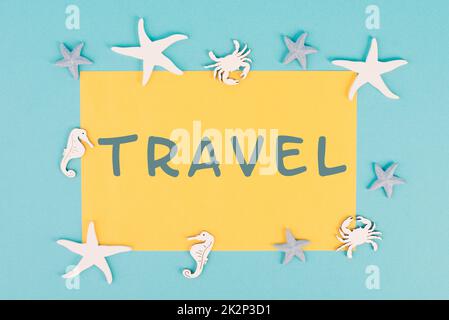 The word travel is standing on a yellow colored paper, sea stars, seahorses and crab bulding a frame, summer vacation, tourism destination Stock Photo