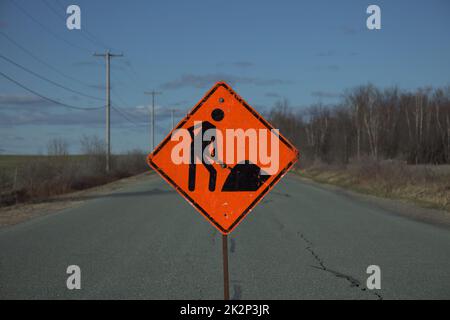 construction orange traffic sign on rural road clouds and electric line Stock Photo