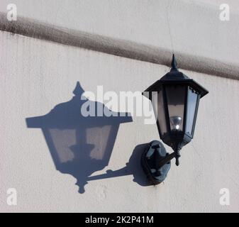 Street lamp mounted on the wall and its shadow Stock Photo