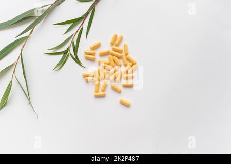 Yellow tablets of nutritional supplements lie on a white background. Place for an inscription. Green line in the background. Stock Photo