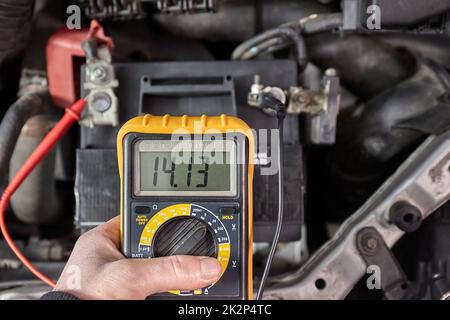 Checking car battery and alternator voltage with running engine Stock Photo