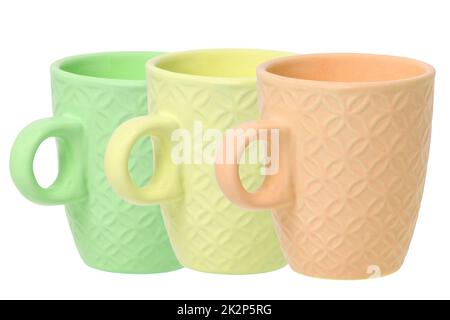 Mug of coffee. Closeup of three empty green, yellow and orange ceramic cups with space for label isolated on a white background. Concept morning coffee. Space. Macro. Stock Photo