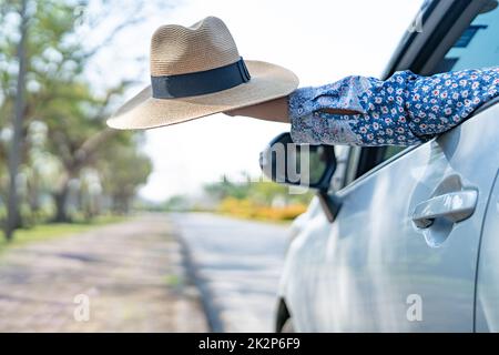 Happy enjoy and freedom in traveling trip with raised hand and holding beautiful hat outside of window car in summer vacation holiday Stock Photo