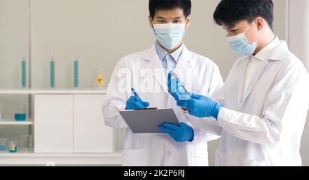 Covid-19 testing in laboratory. Two Scientists discuss about blood samples of patients infected with Coronavirus disease 2019. Healthcare and medical concept. Stock Photo