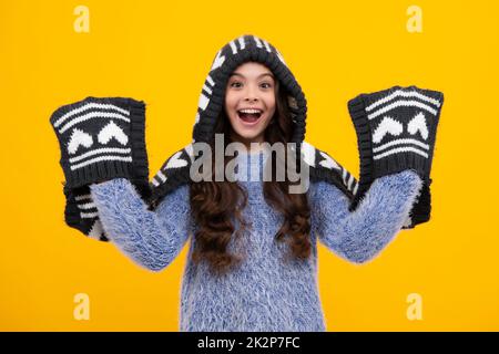 Amazed teenager. Warm hat with hood and scarf. Fashion happy young woman in knitted hat and sweater having fun over colorful blue background Excited Stock Photo