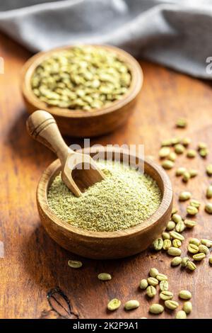 Ground green coffee and unroasted coffee beans in bowl. Stock Photo