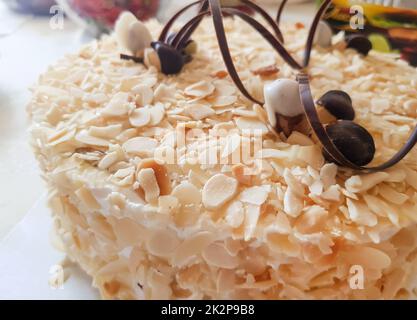 A whole round almond cake decorated with chocolate stripes and nuts. Sweet food. Sweet dessert. Food background. Close-up Stock Photo