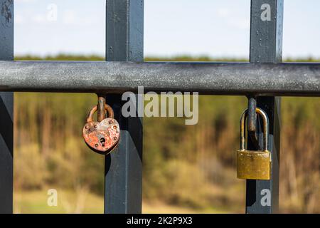 Closeup view of heart-shaped love padlock hanging on a bridge fence Stock Photo