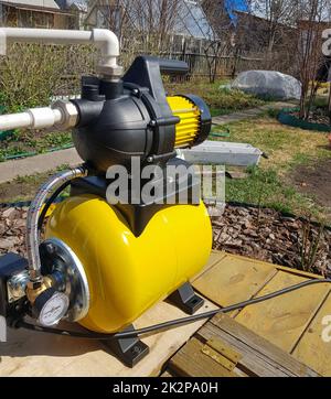 New water pumping station, household automatic station with pressure sensor, yellow color. Application of house, country house, village, cottage Stock Photo