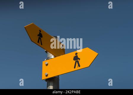 Two yellow signposts with walking figures and arrows point in different directions, Canton Thurgau, Switzerland Stock Photo
