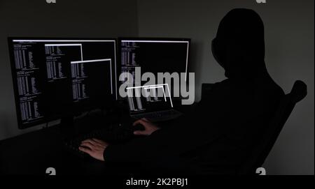 hacker in the dark working on multiple devices Stock Photo