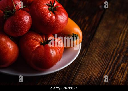 Fresh red and yellow tomatoes on plate Stock Photo