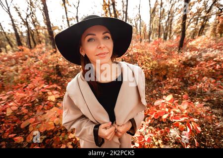 woman in dress and hat on background of autumn foliage Stock Photo