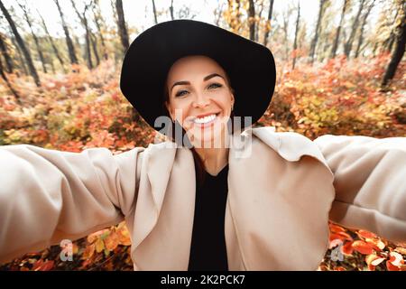 happy woman making selfie in the autumn park full of yellow leaves Stock Photo