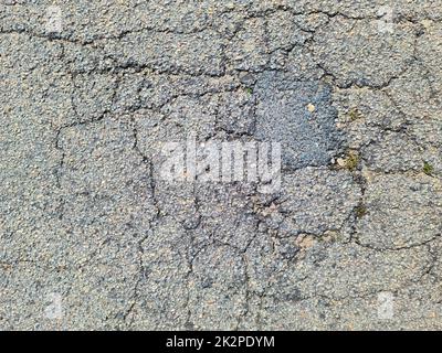 Asphalt surfaces of damaged streets and roads with cracks in a close up. Stock Photo
