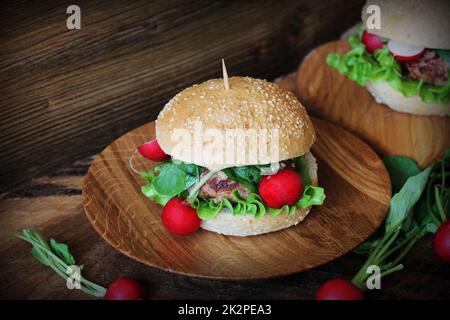 Homemade traditional burgers with beef,radish,lettuce, served on wooden background. Stock Photo