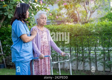 Doctor help and care Asian senior or elderly old lady woman use walker with strong health while walking at park in happy fresh holiday. Stock Photo