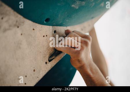 Male hands smeared with magnesium powder grabbing a hold of a climbing wall Stock Photo