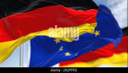 Detail of the national flag of Germany waving in the wind with blurred european union flag in the background on a clear day Stock Photo