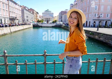 Traveler girl standing on the bridge with beautiful view of Trieste city, Italy Stock Photo