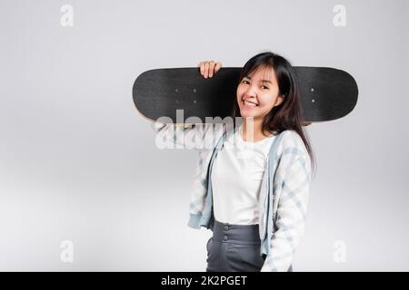 Smiling happy woman holding skateboard on shoulder Stock Photo