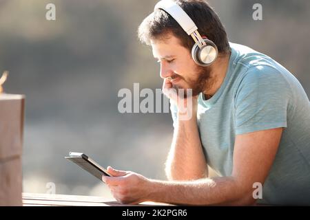 Man watching videos on tablet with headphones Stock Photo