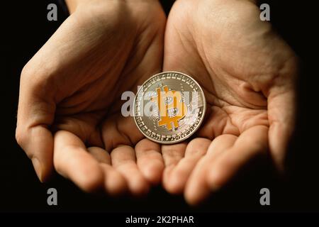 Silver bitcoin cryptocurrency in two hands Stock Photo